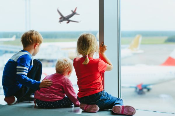 Niños mirando por ventana en aeropuerto